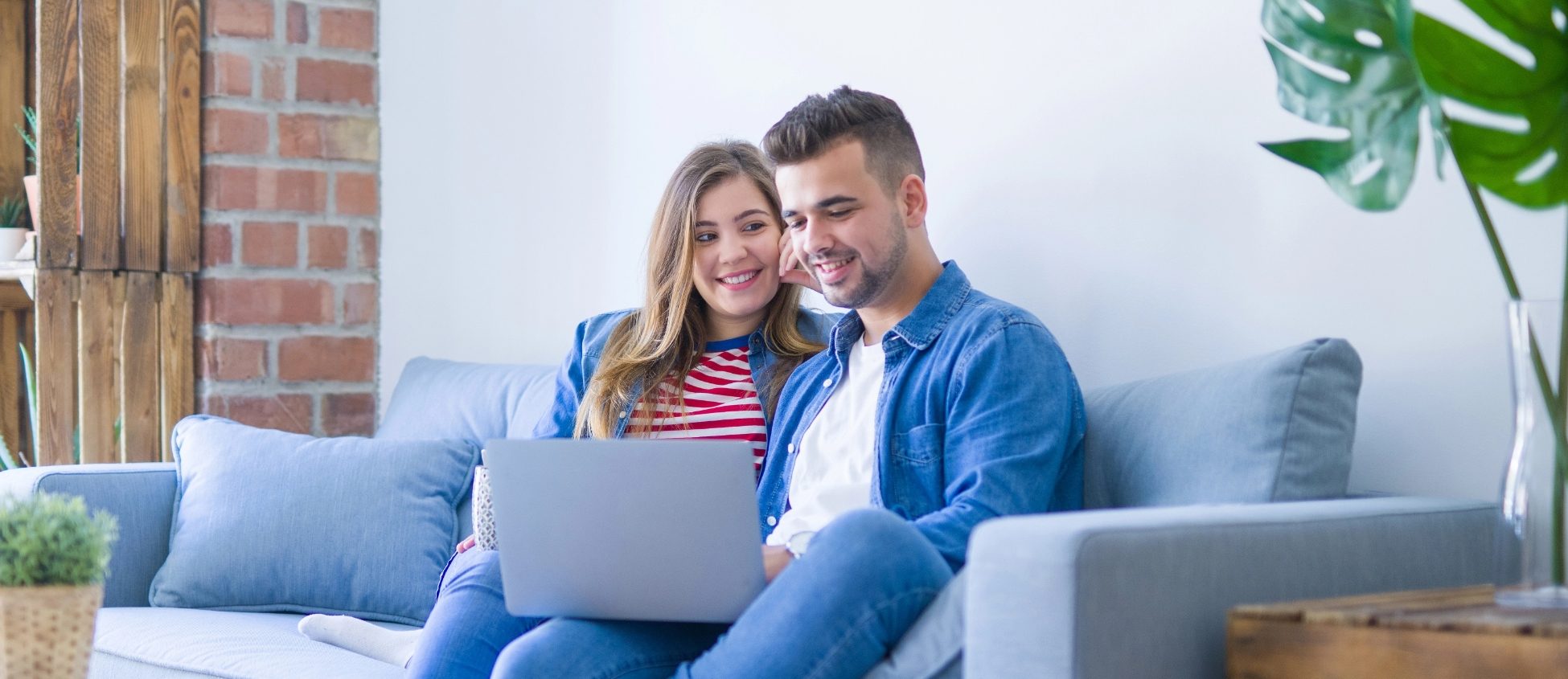 couple sat down on sofa looking at laptop